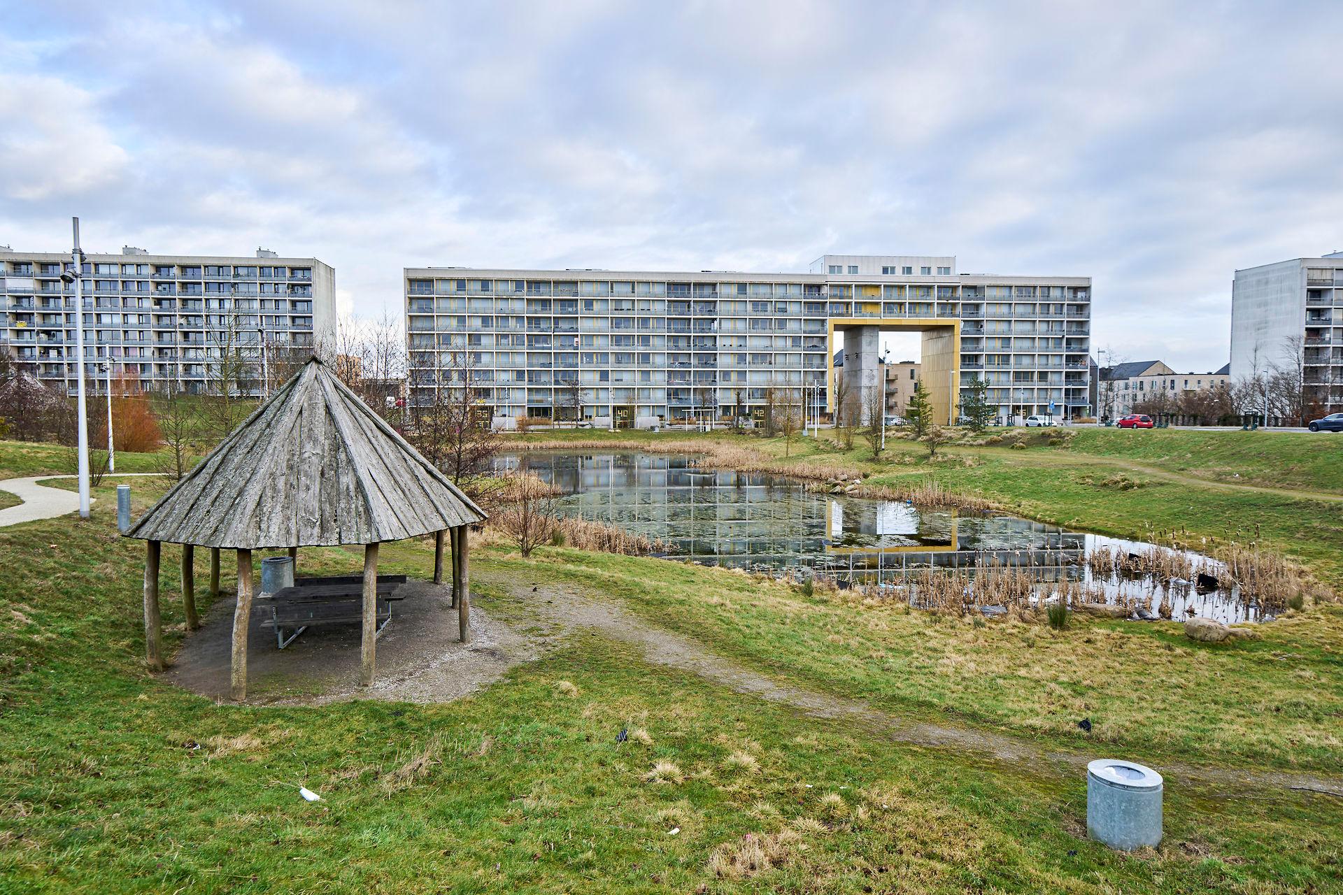 Den meget roste renovering af blok 4 i Gellerup Parken, Aarhus, som for et par år siden blev omdannet til en lokal triumfbue og lysskulptur, er ét af  Lars Autrups eksempler på, at der både menneskeligt og miljømæssigt er meget at vinde ved at bygge om i stedet for at rive ned og bygge nyt. I dette indlæg opfordrer han politikerne til at lette byggeriets muligheder for at tænke   grønt i nye baner.