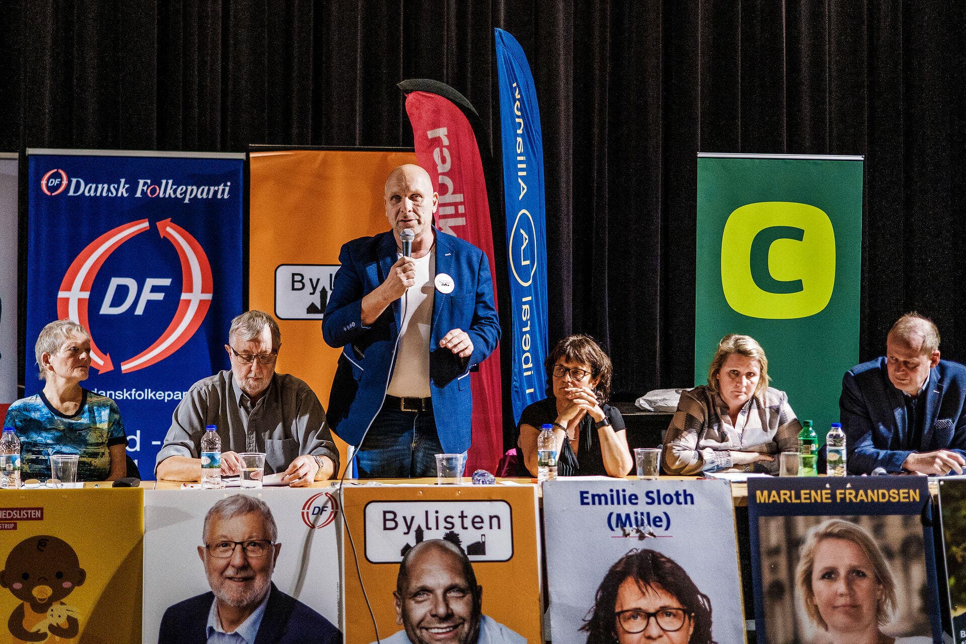 Kandidaterne til KV21 er i fuld gang med debatmøder landet over  - her i Glostrup Bio med Lars Thomsen fra Bylisten ved mikrofonen. Kandidaternes erhverv, alder og køn er netop samlet i oversigt fra KMD.