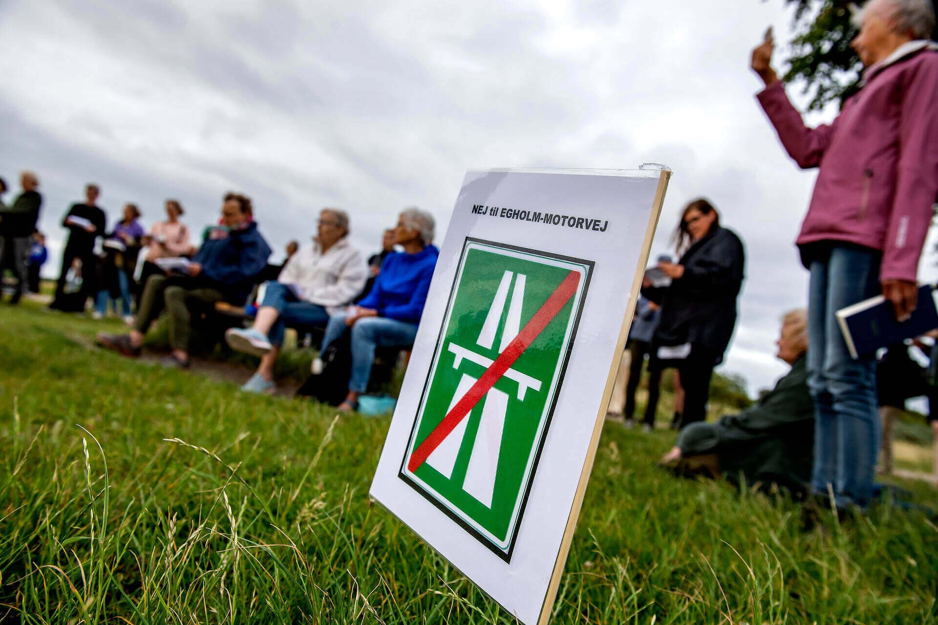 Nye trafikforbindelser over Limfjorden og øen Egholm  vil maltraktere naturområder med asfalt, skriver Susanne Zimmer. Her protesterer en gruppe borgere med fællessang; Blæsten går frisk over Limfjordens vande. 