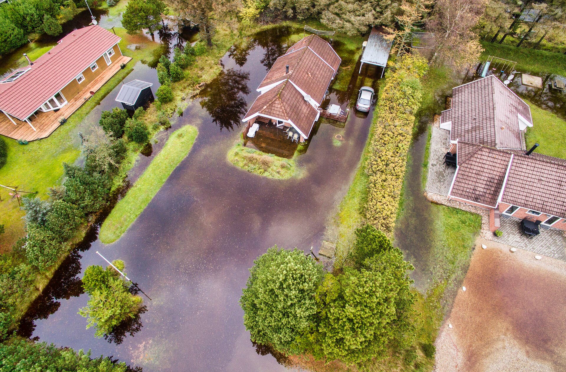 Når oversvømmelserne rammer, er det langt fra alle huse, der bliver ramt lige hårdt, som dette dronefoto fra Vejle tydeligt viser. Derfor kan det være svært at blive enige om, hvordan man skal fordele regningen mellem fx sommerhusejere. Et oplæg til en fælles national fordelingsmodel er forsinket på grund af valget. 