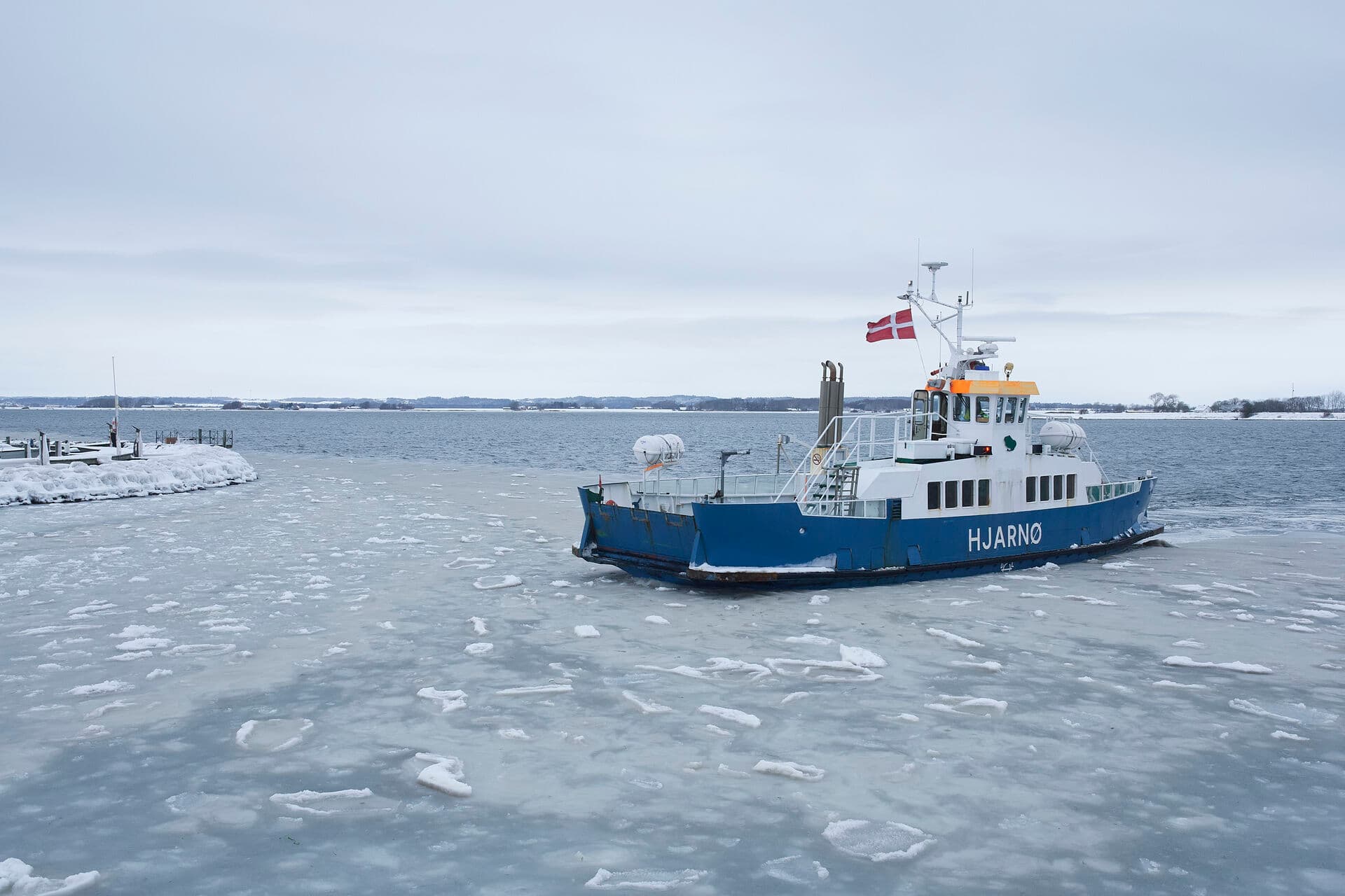 Landet over sejler gamle dieseldrevne færger til de danske småøer. At omstille til el vil koste kommunerne dyrt. Her ses Hjarnøfærgen på vej gennem isen i Snaptun havn.