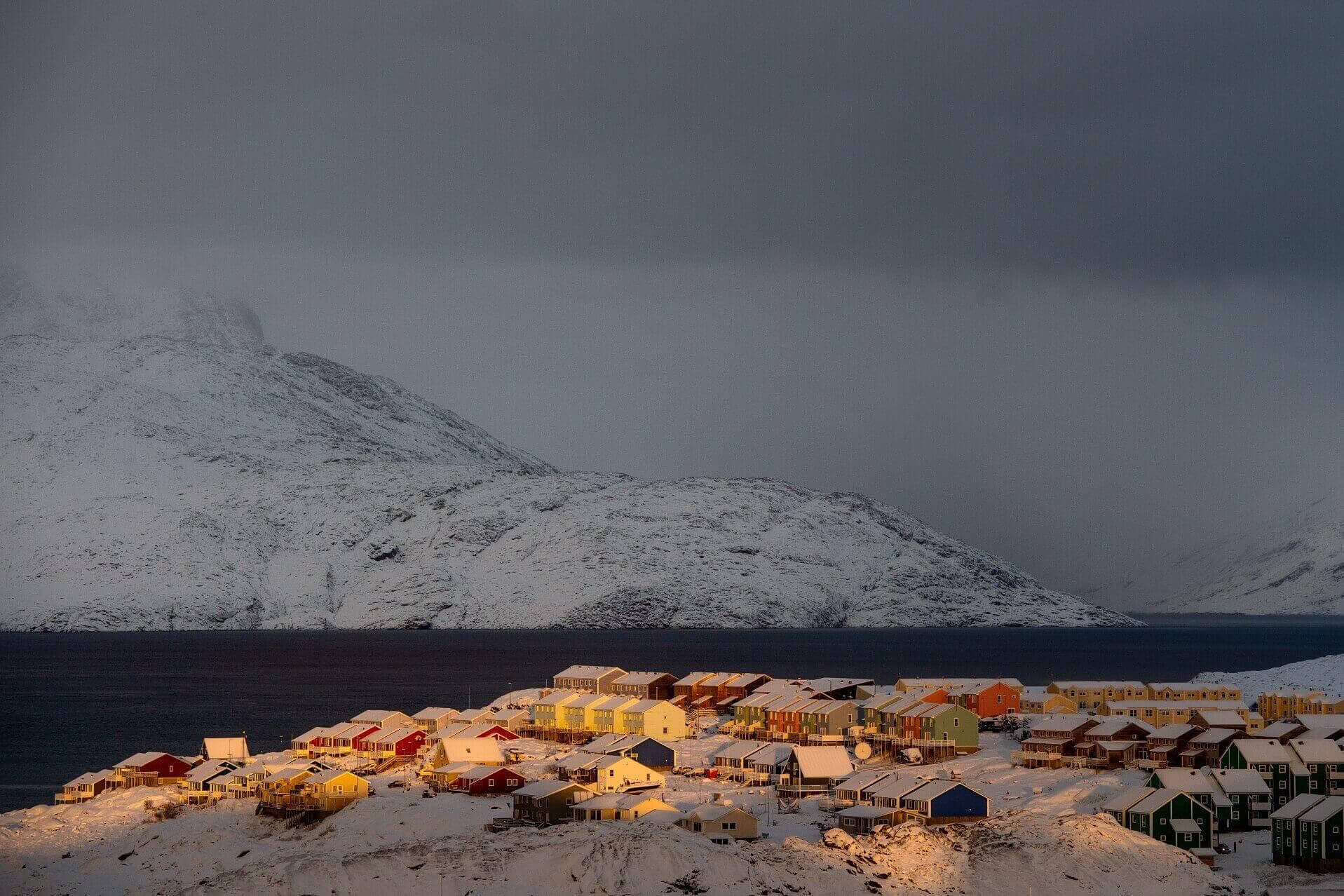 Et glimt af sol efter storm. Et foto, der viser, at byens sjæl er mange ting. Med den globale urbanisering er vi vant til at tænke byer i større skala, stor volumen og med ret ens arkitektur. Men her ser vi træhuse og isbjerge – der er helt unikt for Nuuk og byens sjæl der, siger juryen om dette billede i årets konkurrence. 