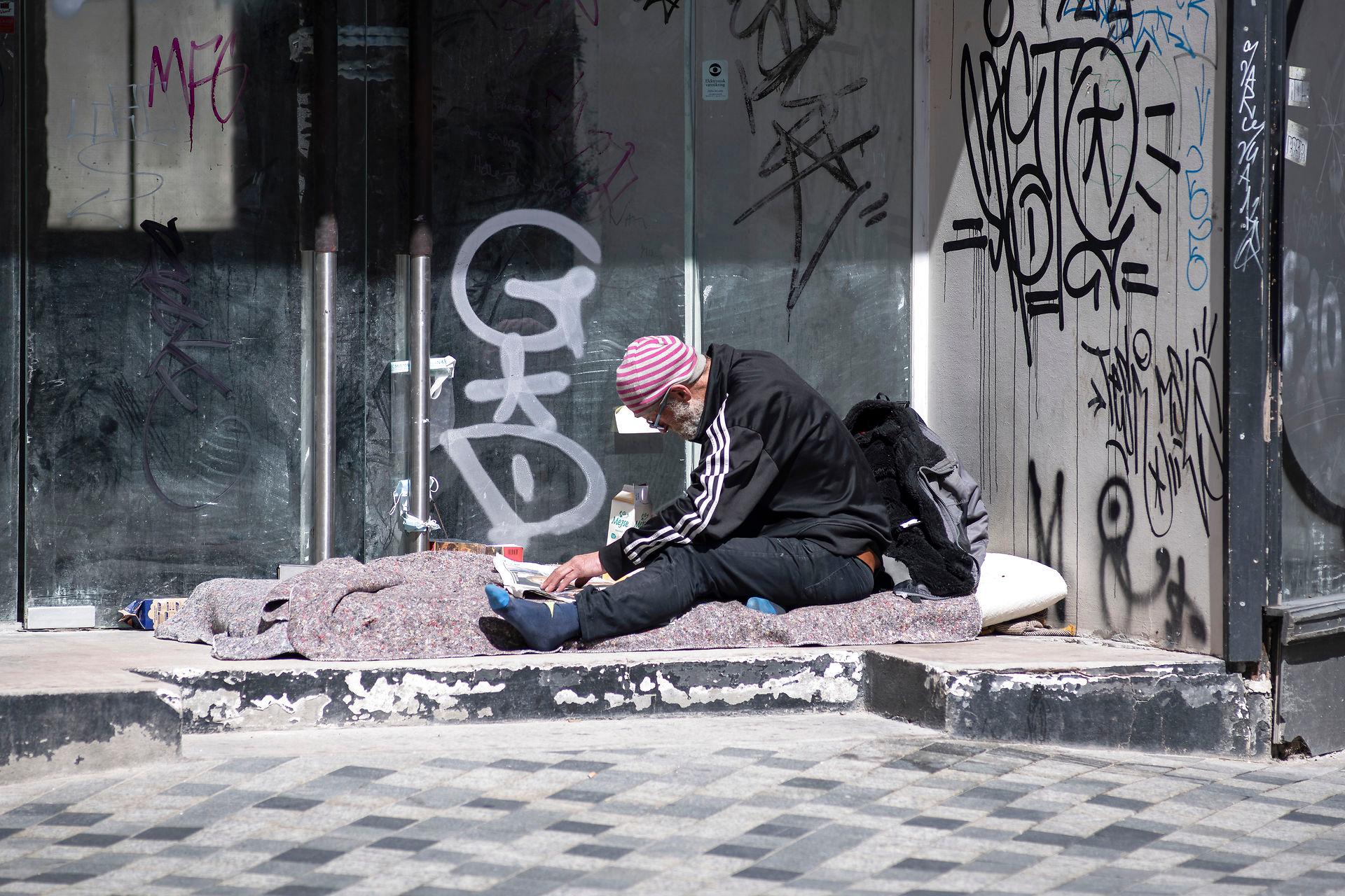 Hjemløs mand læser avis i indgang til forladt og nedslidt butik fuld af graffiti på Købmagergade
(Arkivfoto)